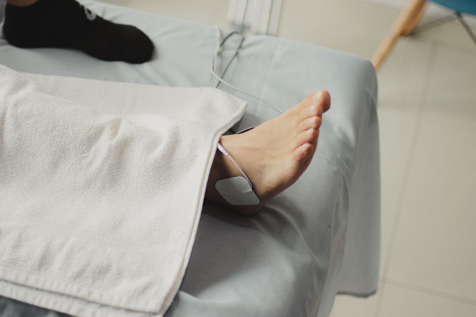 Kuvituskuva: hoitopöytä, pyyhe ja hoitolaite, vain jalka näkyvissä